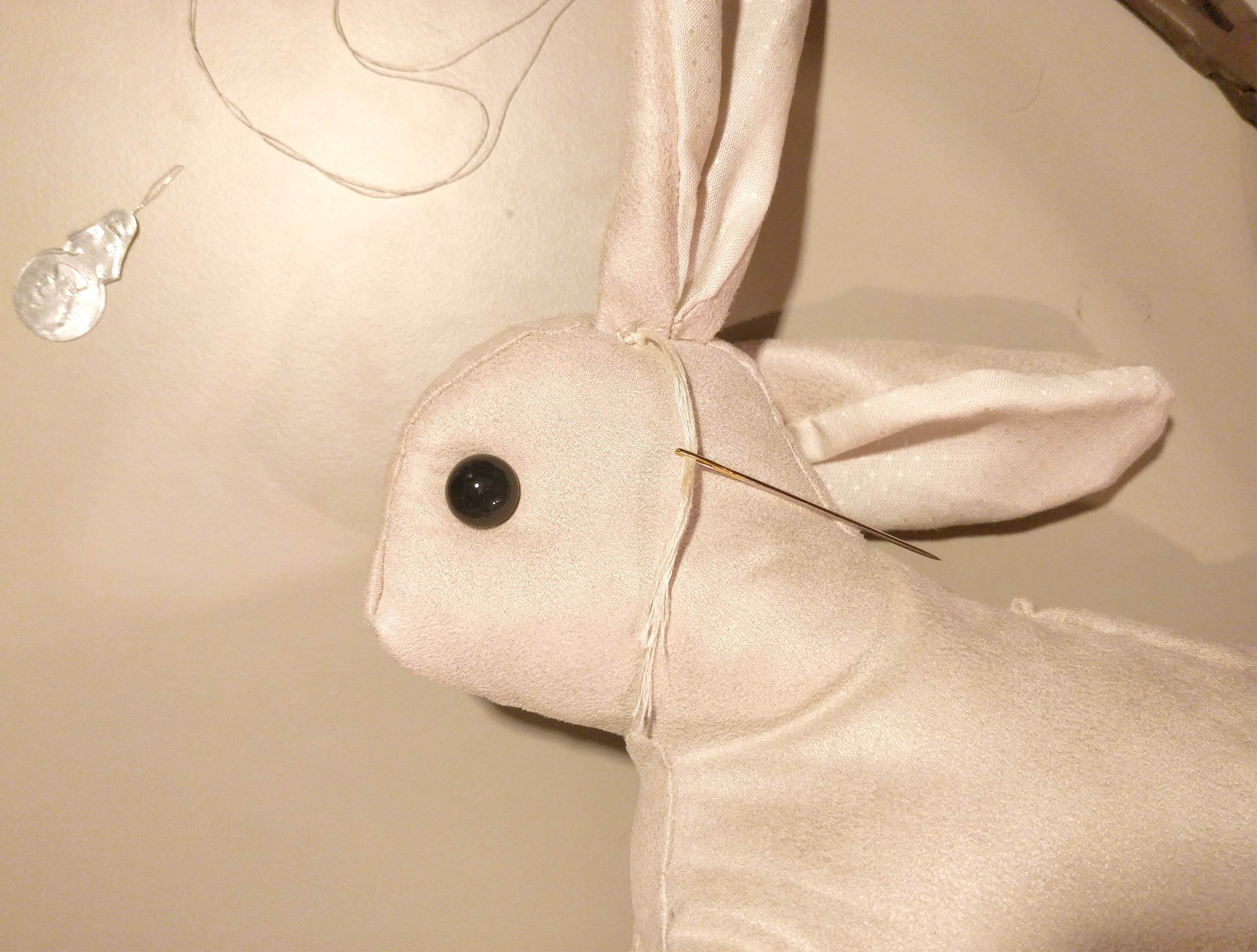 The rabbit's glass eyes are held pretty securely in place using embroidery thread that ties them together through the head, and tied off under the ear.