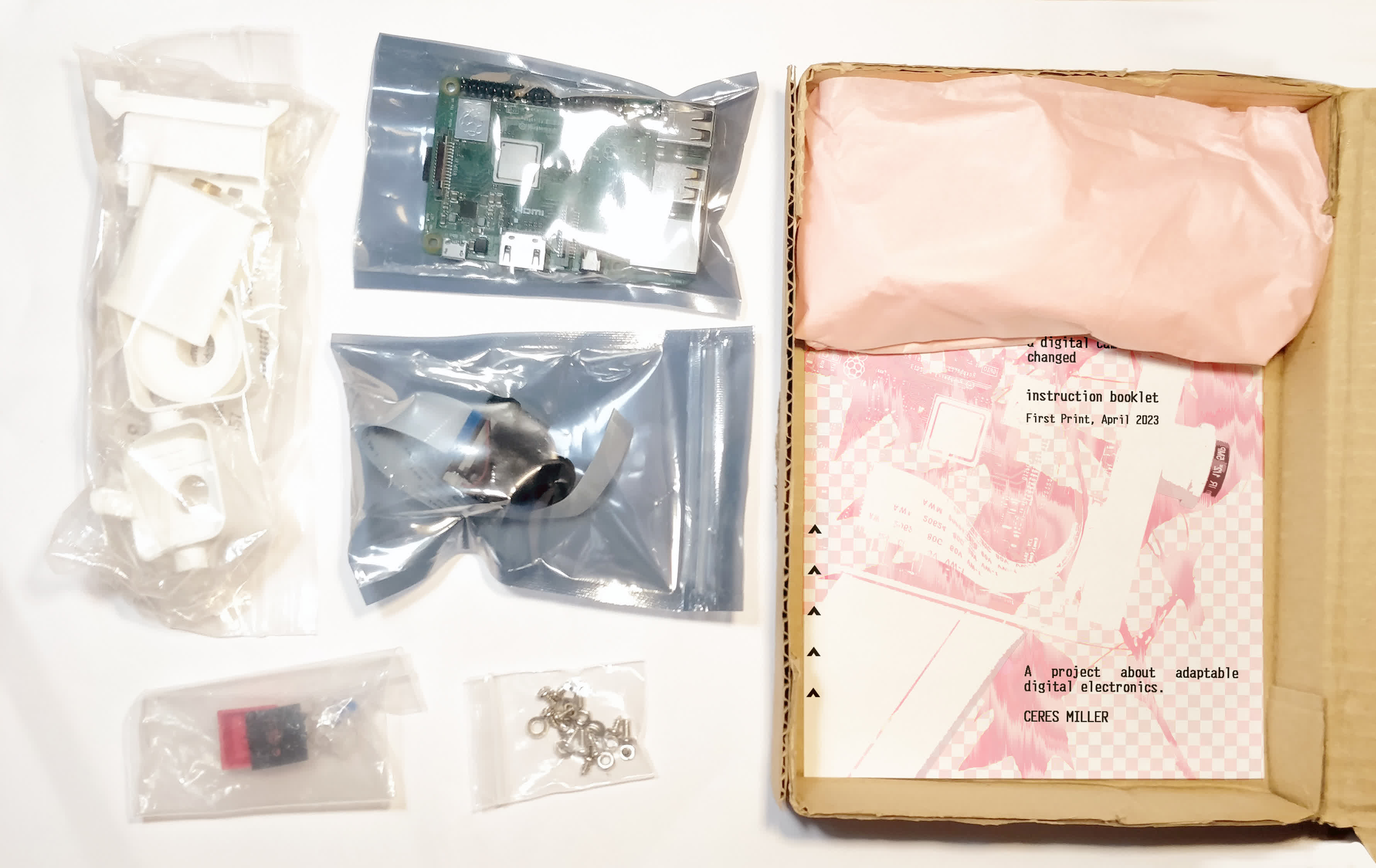 the packaged camera, showing the brass parts wrapped in pink tissue paper, and the instruction booklet. The packaging is meant for postage, and is A5 size x 40mm