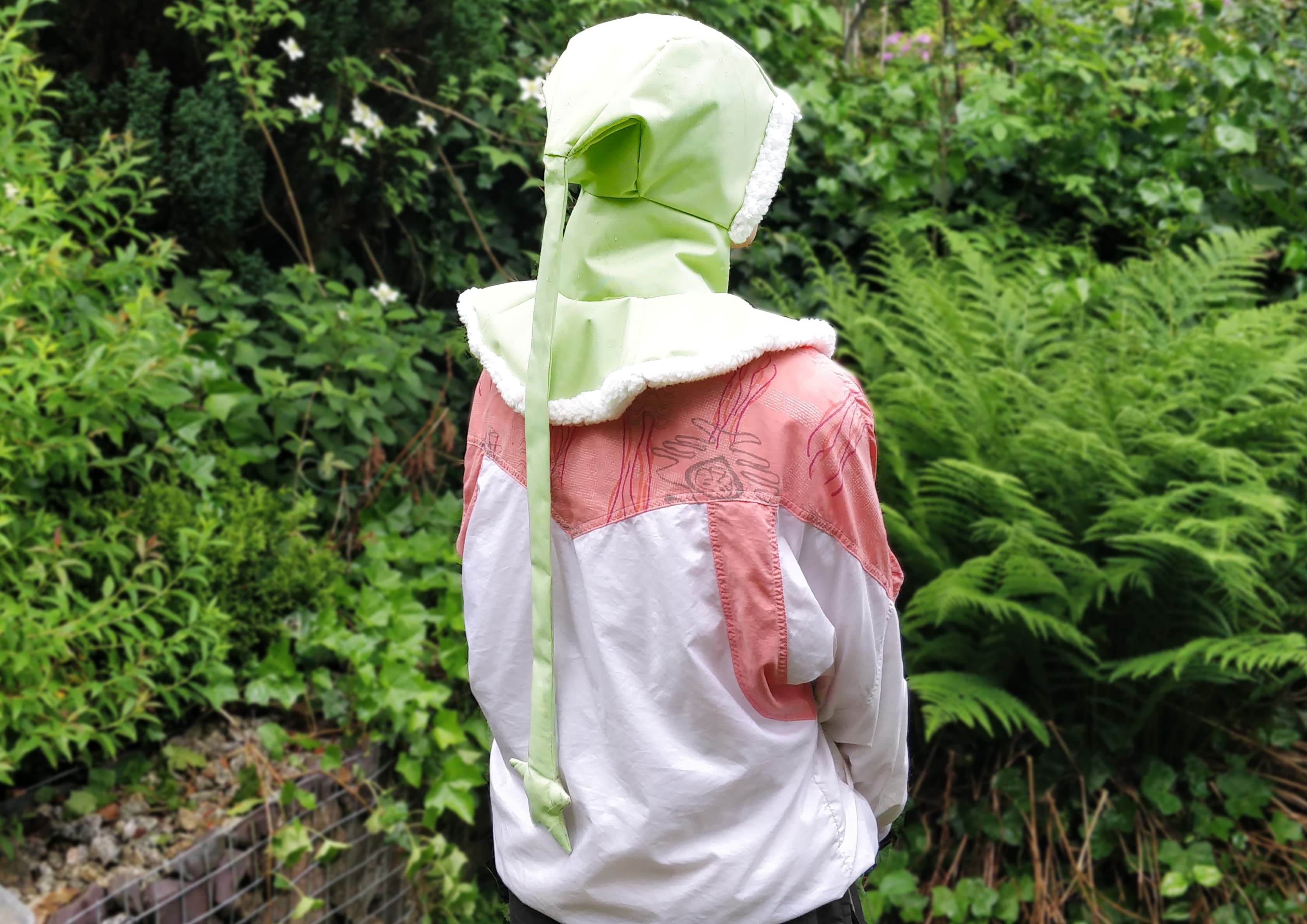 A green liripipe rain hood, made from cordura, showing the back and star-ended tail